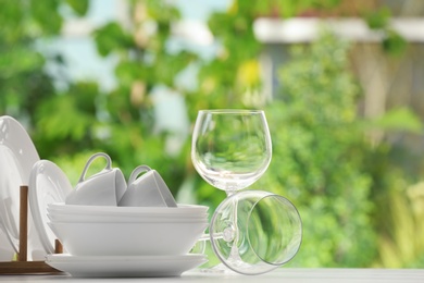 Photo of Set of clean dishware on table against blurred background. Space for text