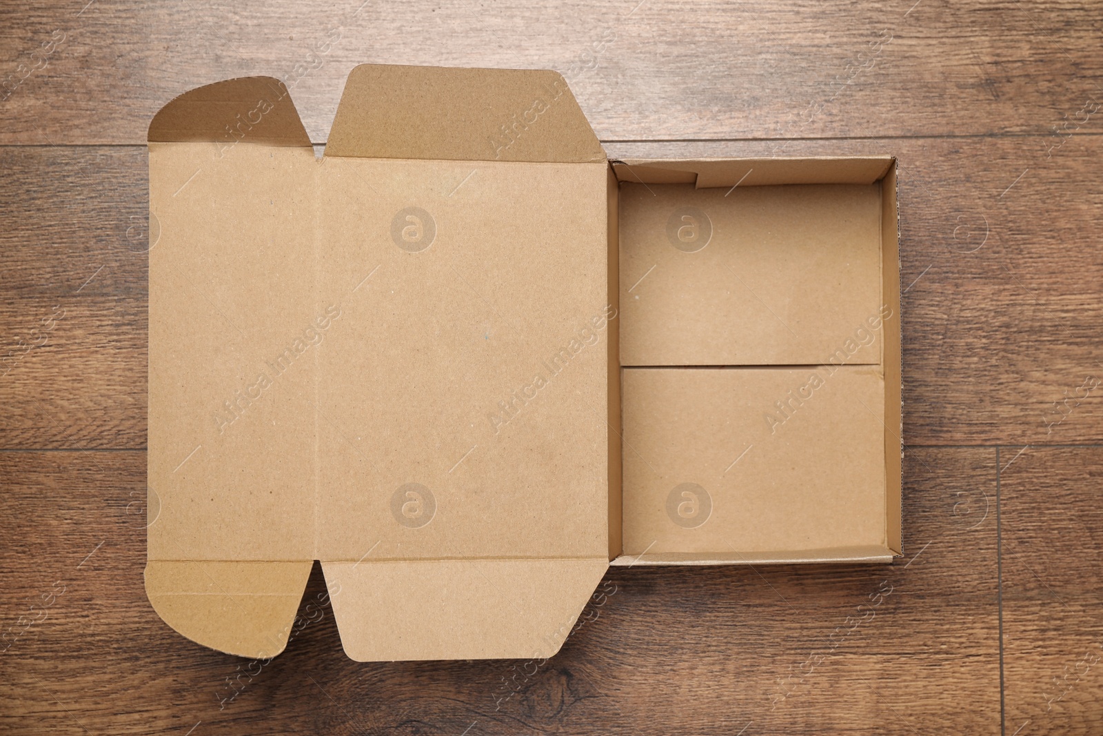 Photo of Open cardboard box on wooden background, top view