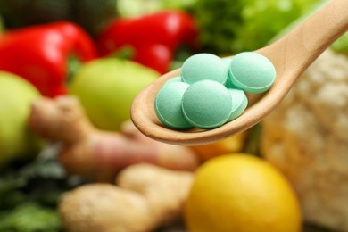 Photo of Dietary supplements in wooden spoon near products, closeup. Space for text