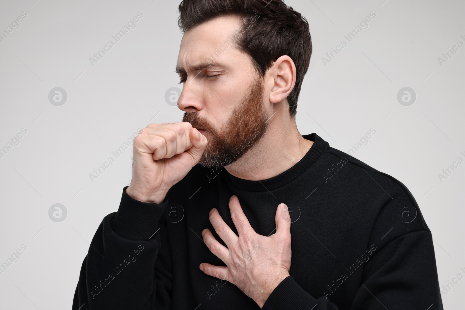 Photo of Sick man coughing on light grey background. Cold symptoms