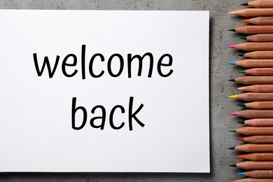 Image of Paper with phrase Welcome Back and pencils on grey table, flat lay