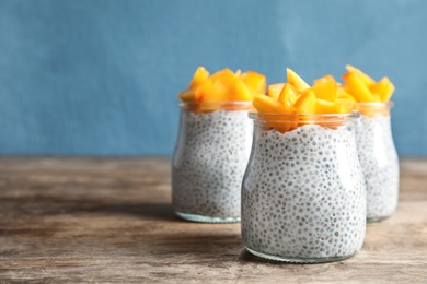 Jars of tasty chia seed pudding with persimmon on table, space for text