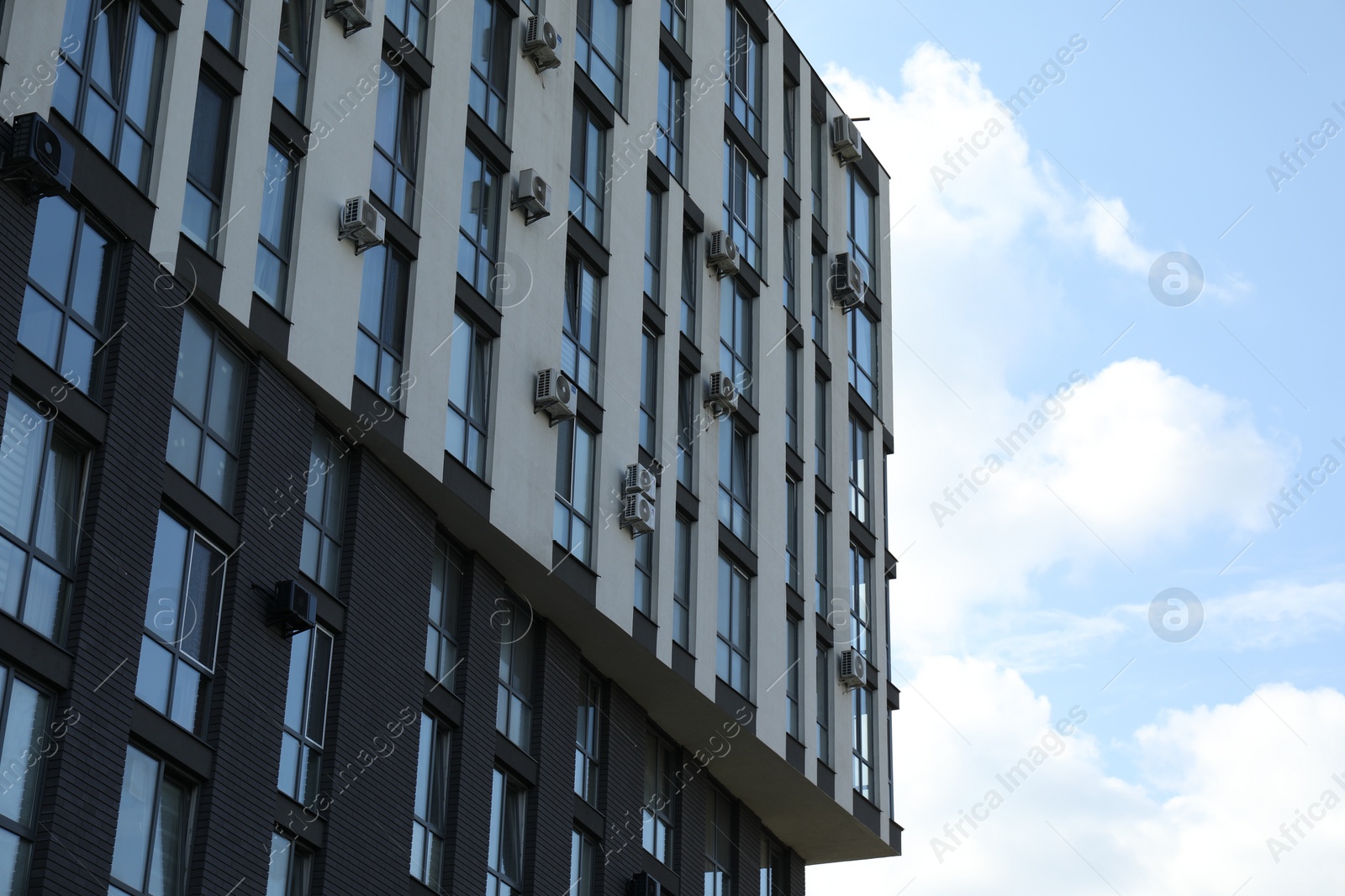 Photo of Modern building with big windows against blue sky outdoors, space for text