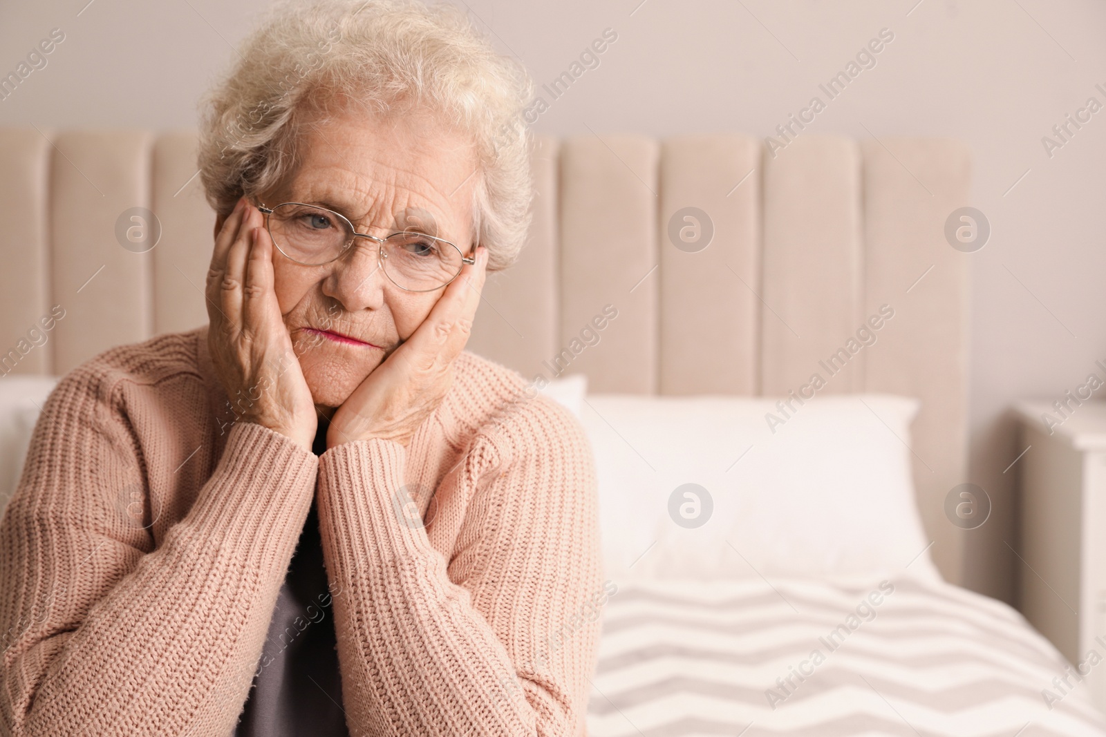 Photo of Senior woman with headache in bedroom at home. Space for text