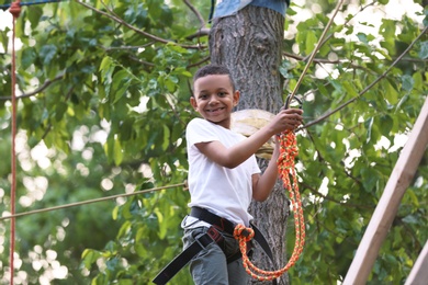 Photo of Little African-American boy climbing in adventure park. Summer camp