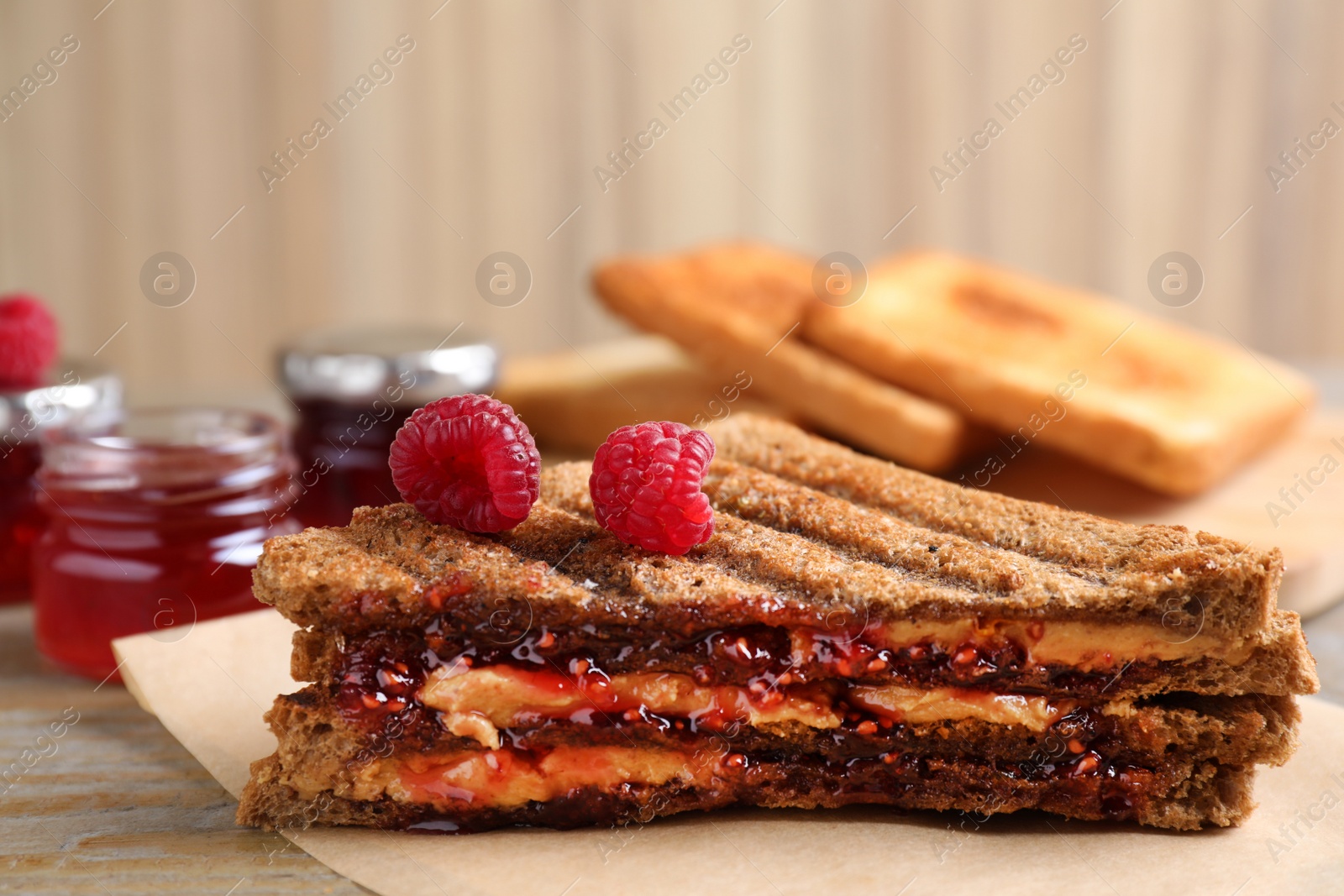 Image of Tasty sandwich with raspberry jam and peanut butter for breakfast on table