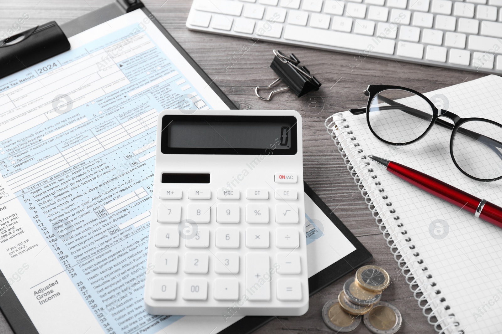 Photo of Tax accounting. Calculator, document, stationery and coins on wooden table, closeup