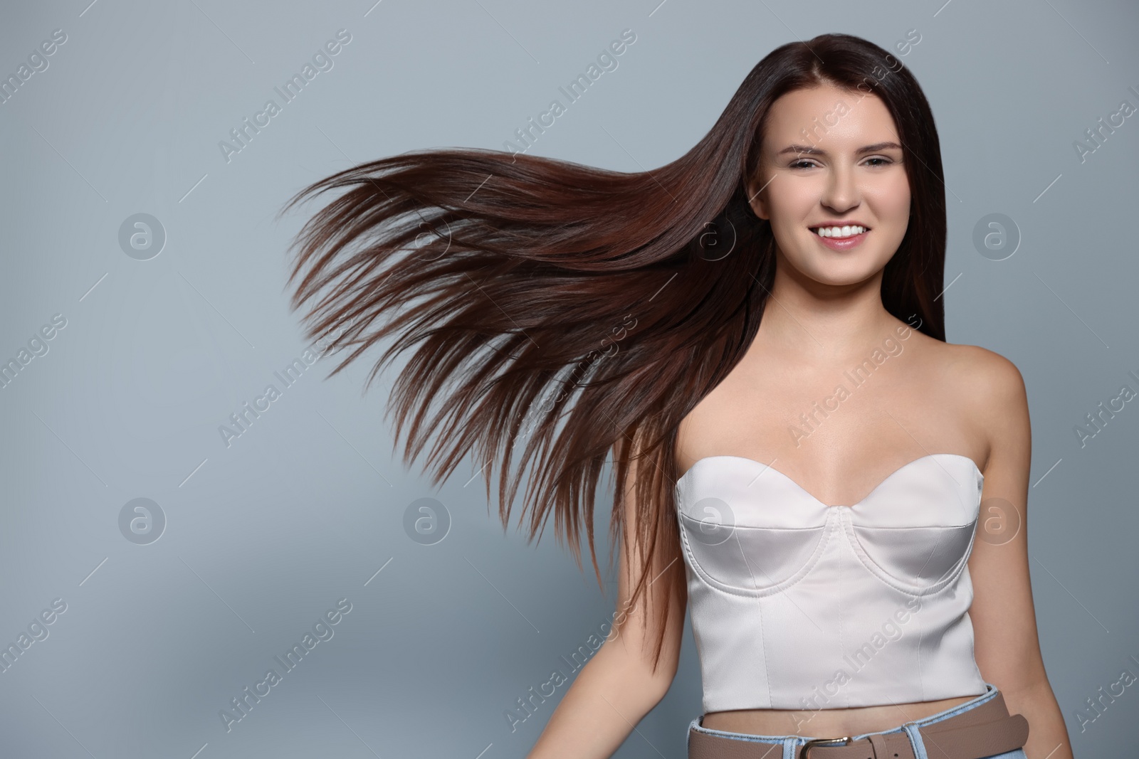 Photo of Portrait of beautiful young woman with healthy strong hair on light gray background