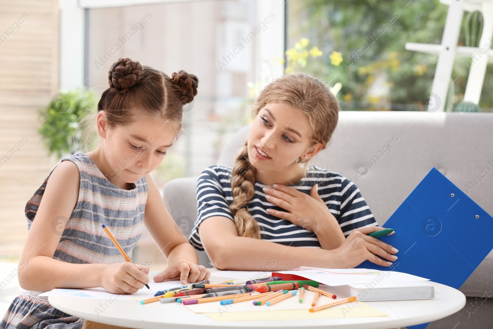 Photo of Young female psychologist working with little child in office