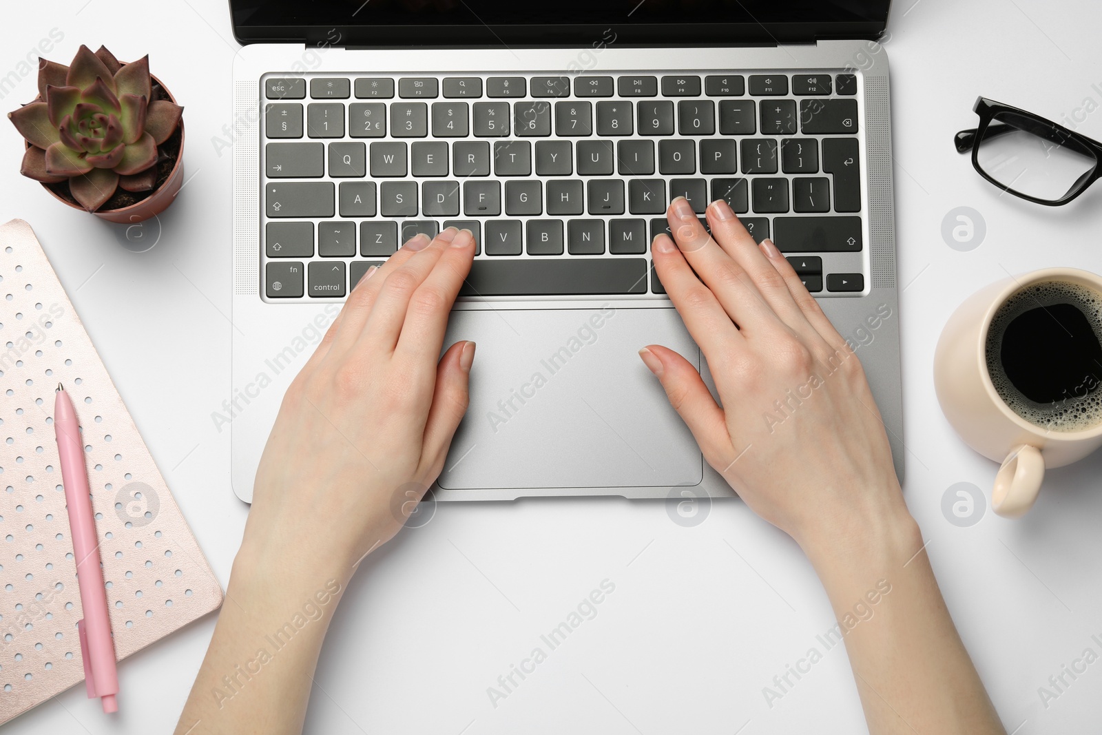 Photo of Woman using laptop at white table, top view