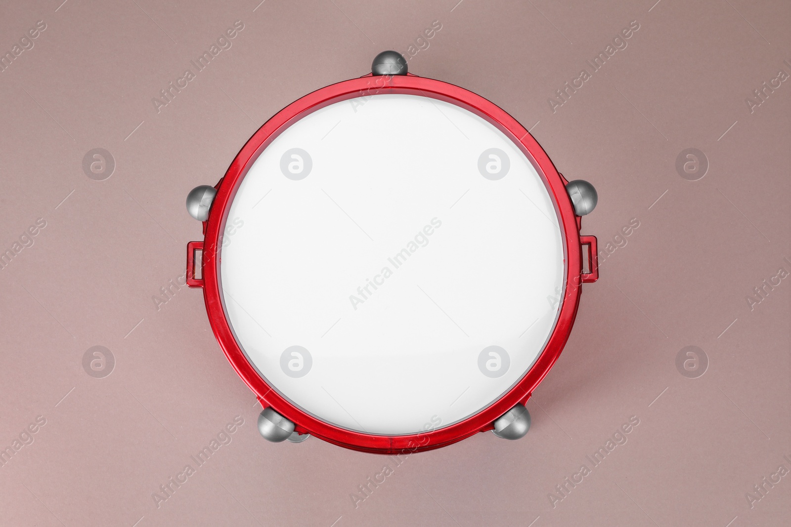 Photo of Drum on dusty rose background, top view. Percussion musical instrument