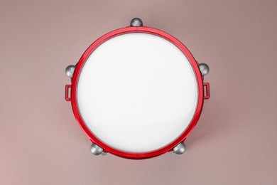 Photo of Drum on dusty rose background, top view. Percussion musical instrument