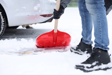 Man removing snow with shovel near car outdoors, closeup