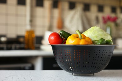 Photo of Metal colander with different wet vegetables on white textured table