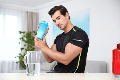 Photo of Young athletic man with protein shake at home