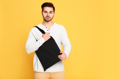 Photo of Portrait of young man with eco bag on yellow background. Space for text
