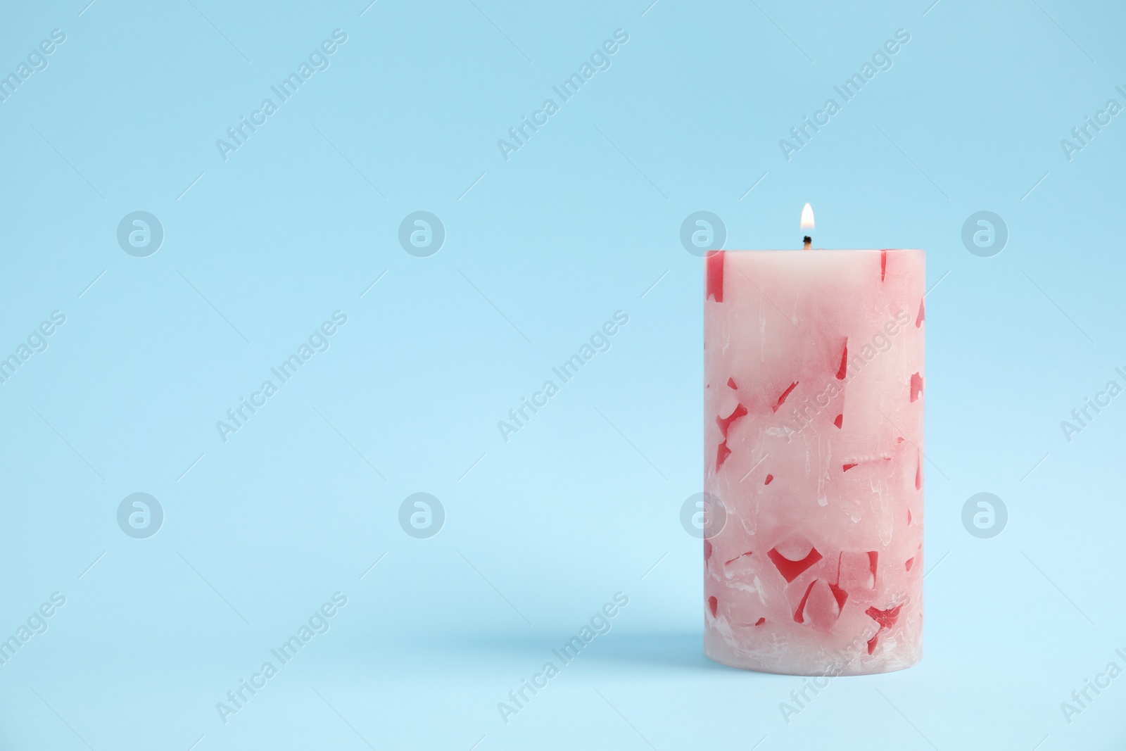 Photo of Alight wax candle on color background. Space for text