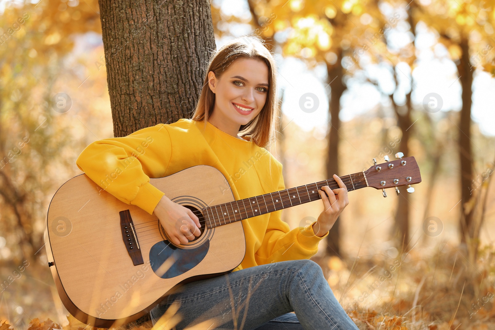 Photo of Teen girl playing guitar in autumn park