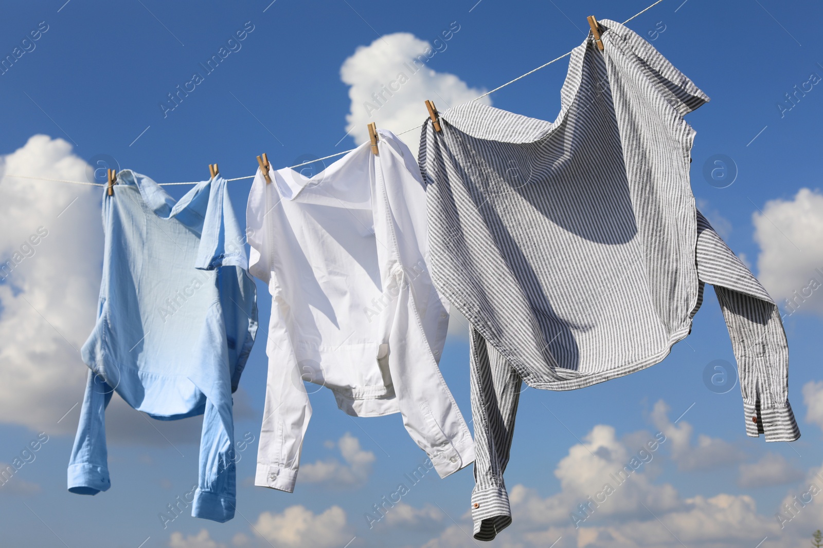 Photo of Clean clothes hanging on washing line against sky. Drying laundry