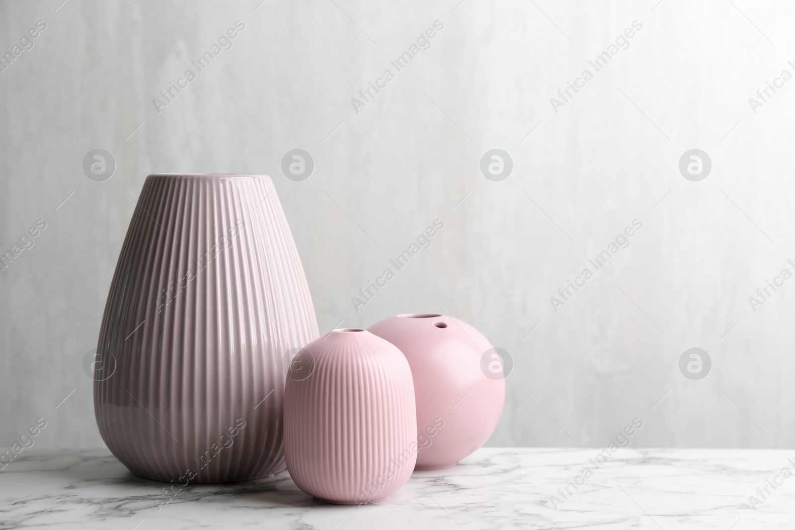 Photo of Stylish empty ceramic vases on white marble table, space for text