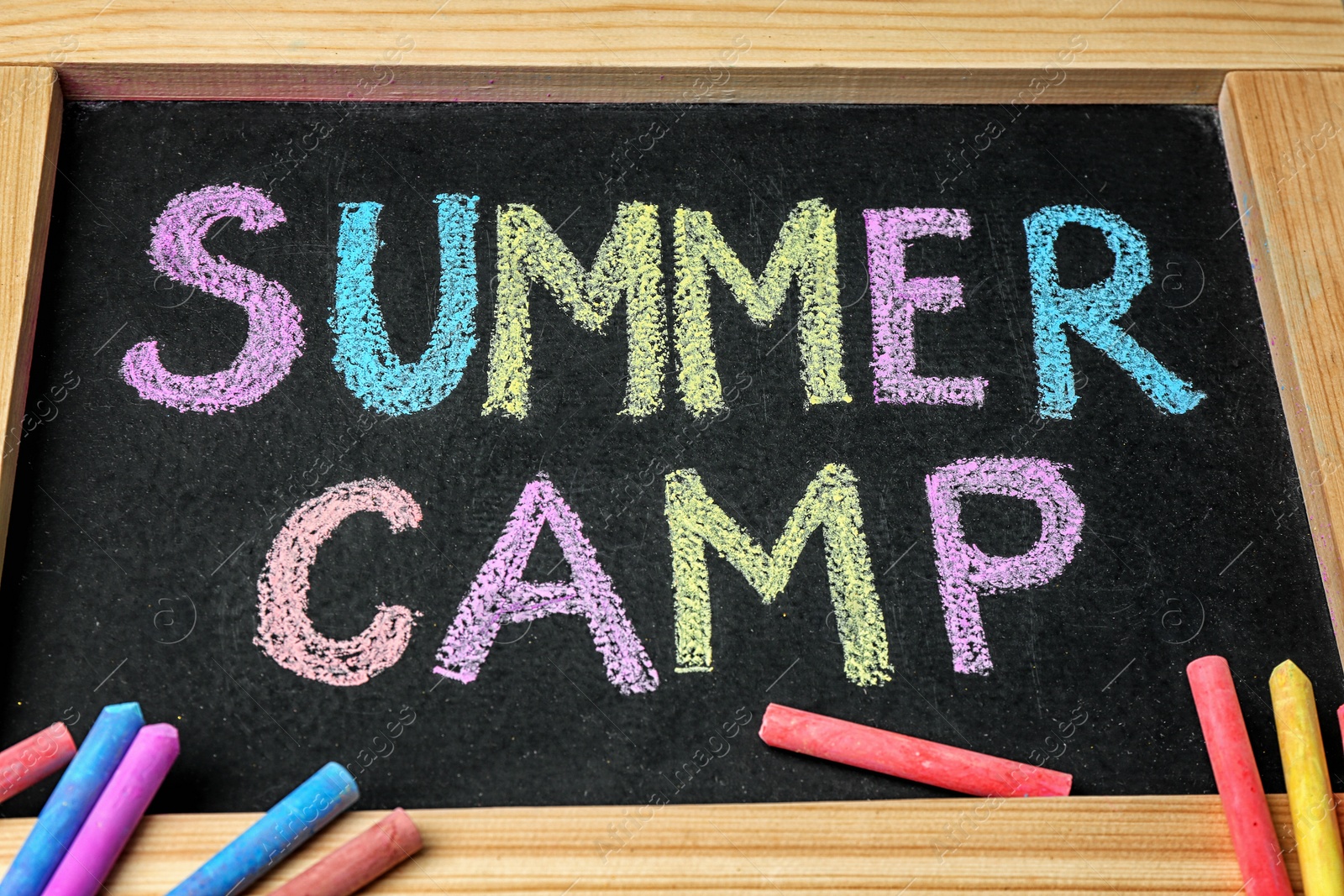 Photo of Blackboard with text SUMMER CAMP chalked in different colors, closeup