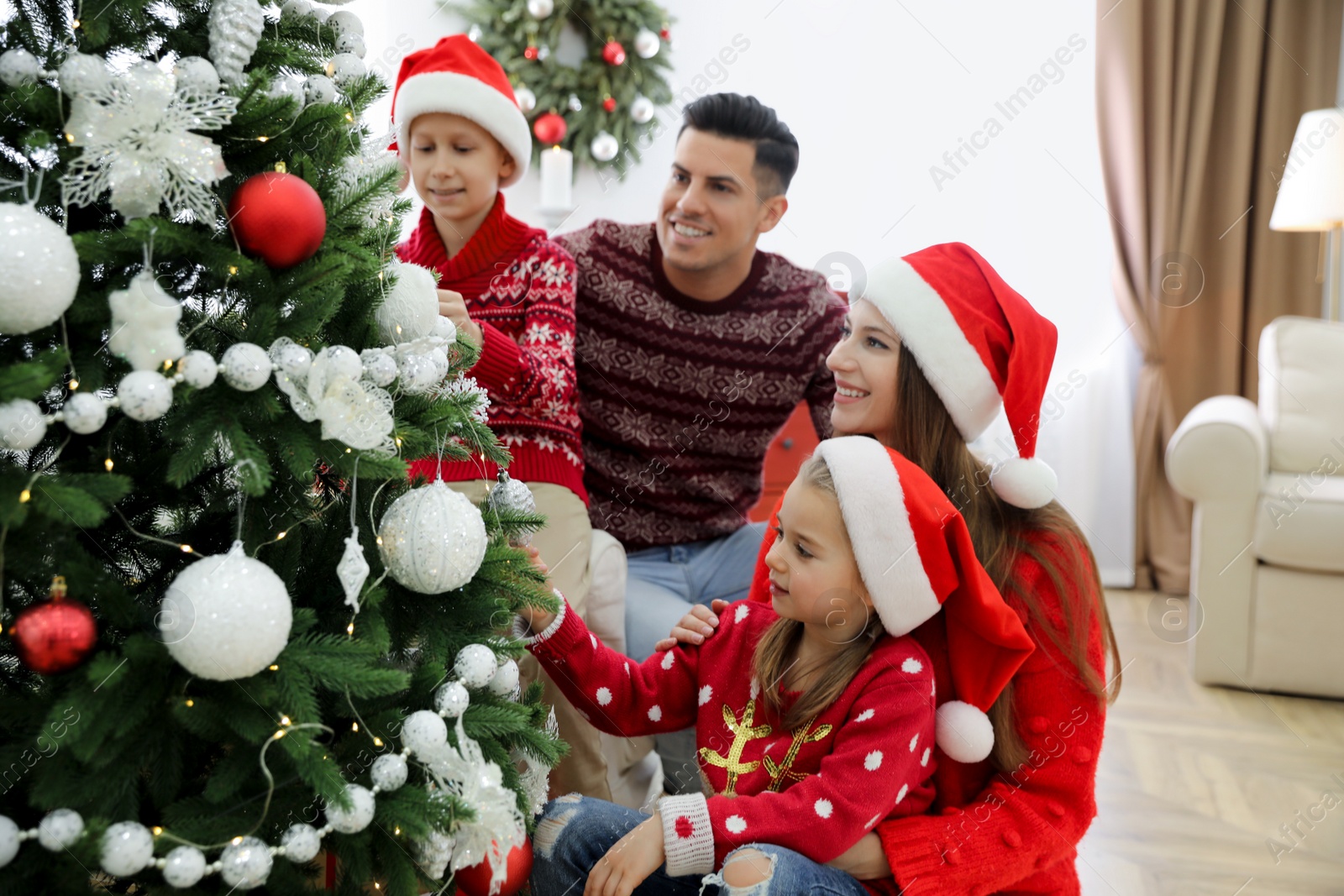 Photo of Happy family with cute children decorating Christmas tree together at home