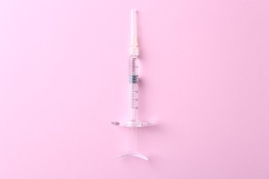 Cosmetology. Medical syringe on pink background, top view