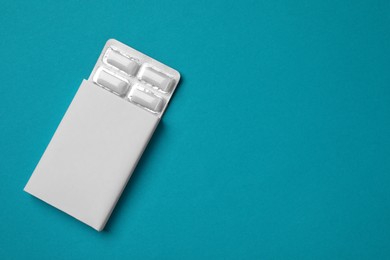 Photo of Pack with tasty chewing gums on turquoise background, top view. Space for text