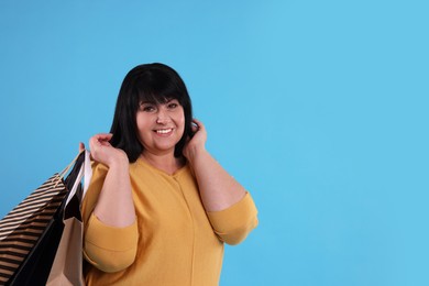 Photo of Beautiful overweight mature woman with shopping bags on turquoise background. Space for text