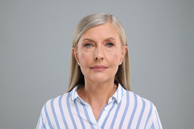 Portrait of beautiful senior woman on light grey background