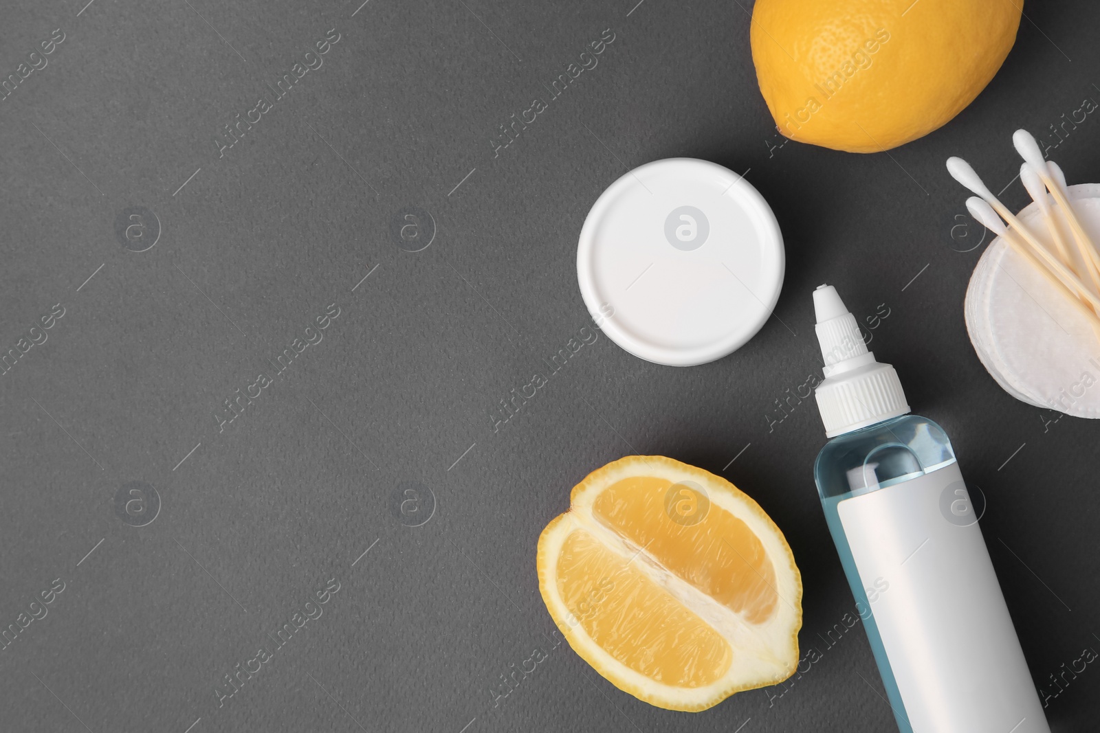 Photo of Lemon face cleanser. Fresh citrus fruits and personal care products on dark grey background, flat lay. Space for text