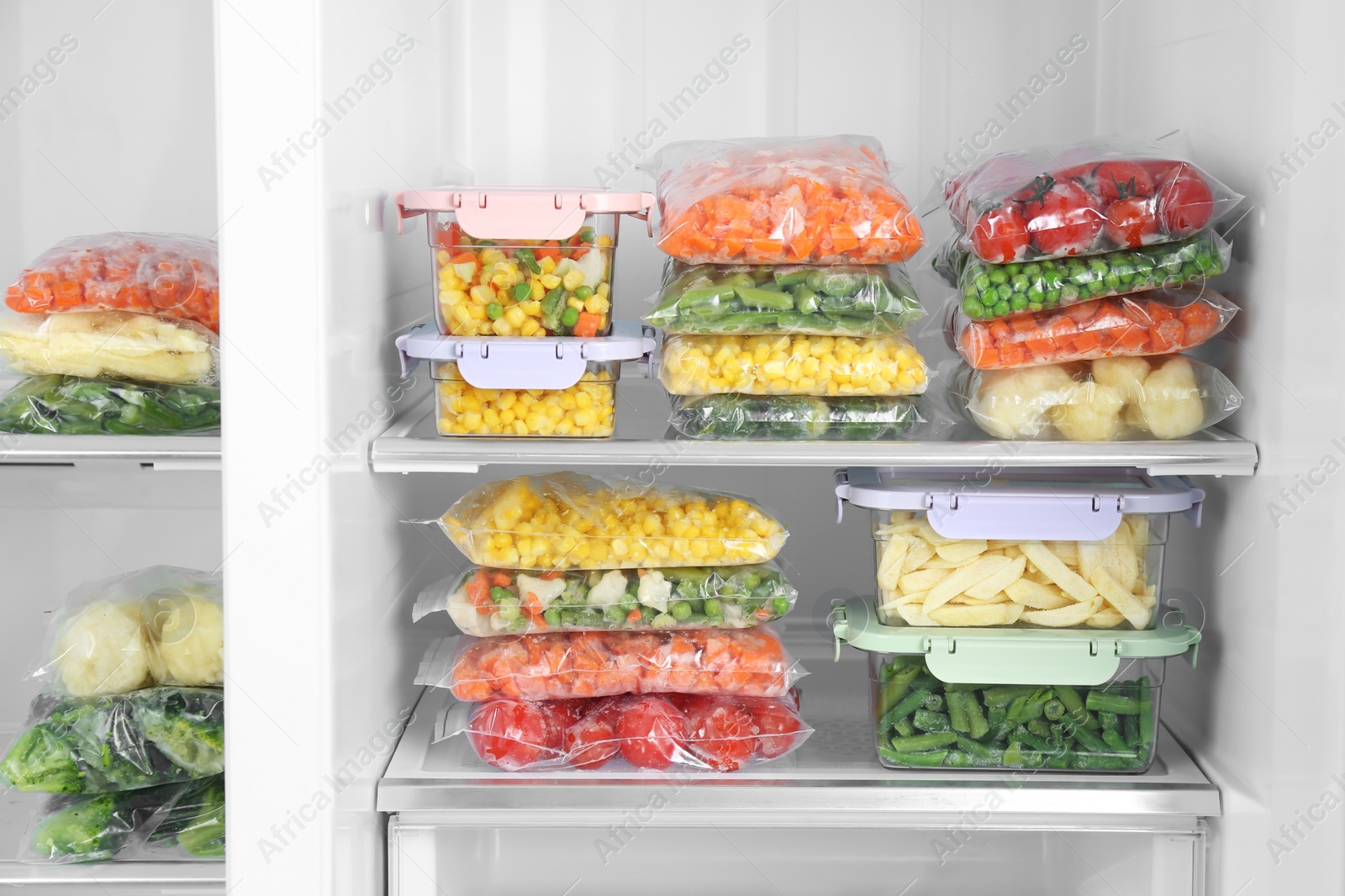 Photo of Plastic bags and containers with different frozen vegetables in refrigerator