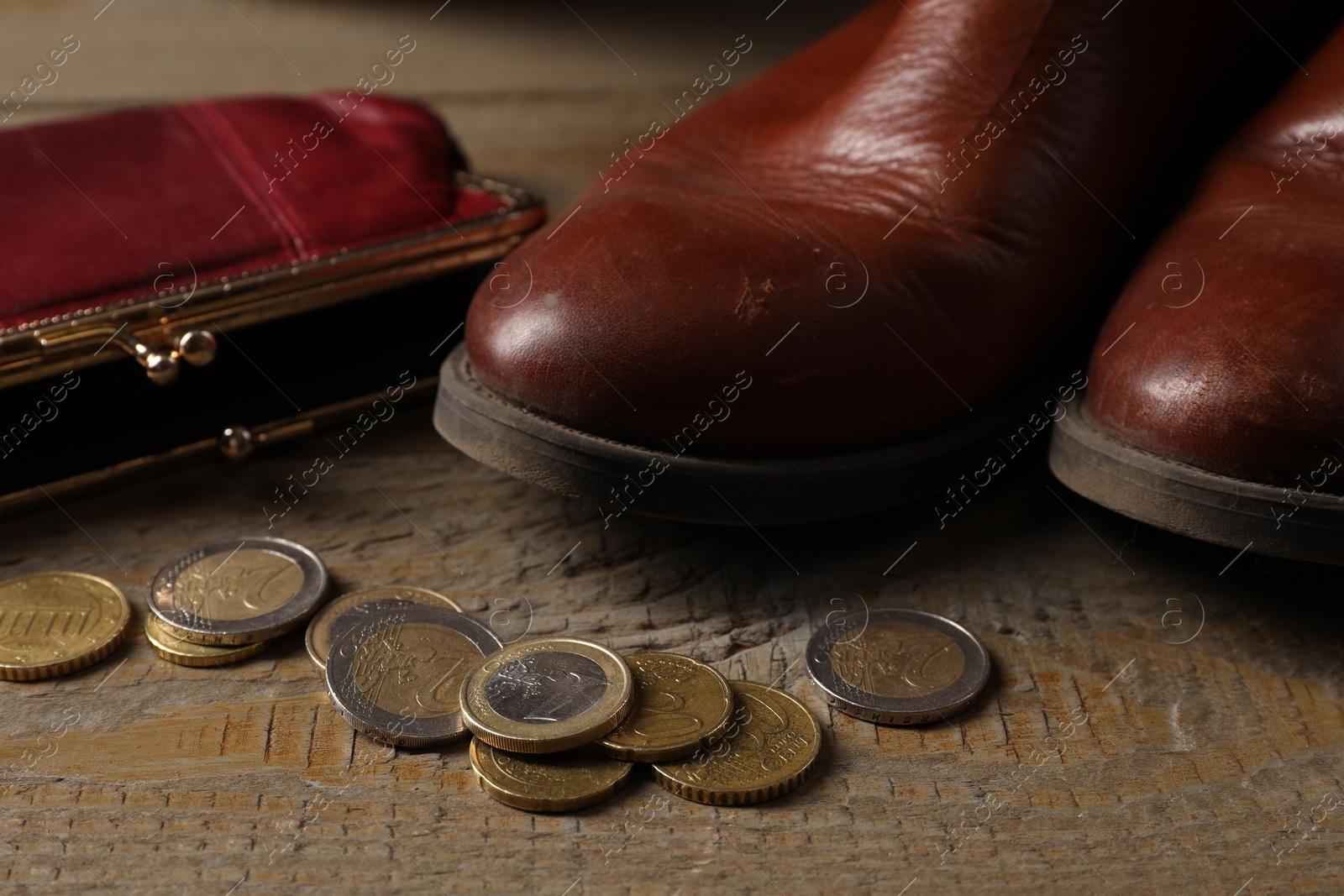 Photo of Poverty. Old boots, wallet and coins on wooden table, closeup