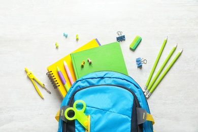 Flat lay composition with backpack and school stationery on light background