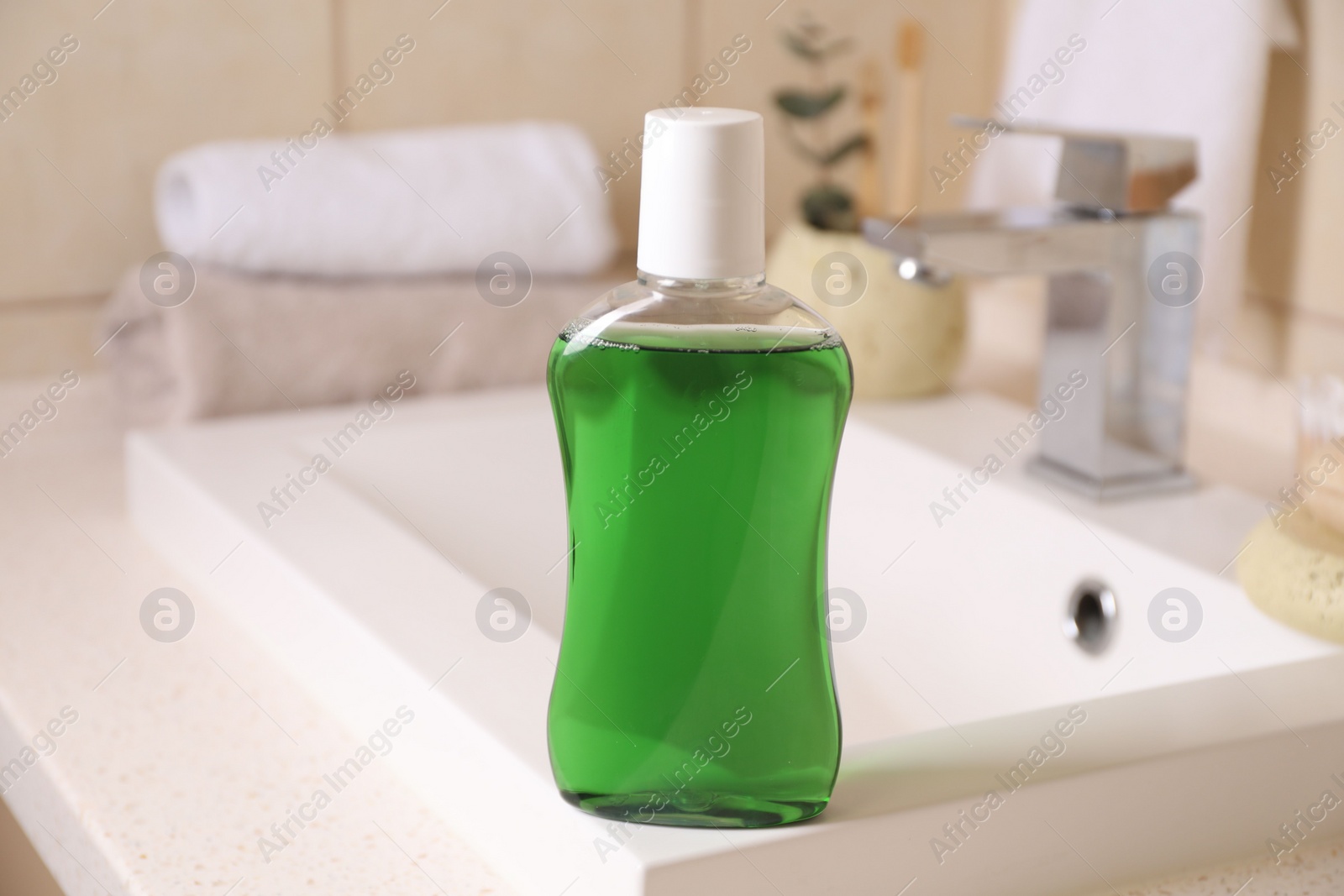 Photo of Fresh mouthwash in bottle on sink in bathroom, closeup