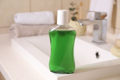 Photo of Fresh mouthwash in bottle on sink in bathroom, closeup