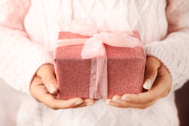 Photo of Woman holding beautiful Christmas gift with bow, closeup
