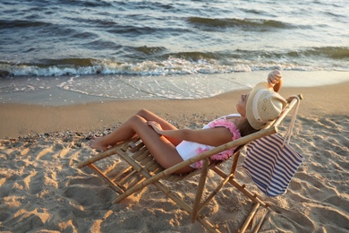 Photo of Young woman relaxing in deck chair on beach