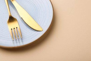 Photo of Setting with stylish cutlery on beige table, above view. Space for text