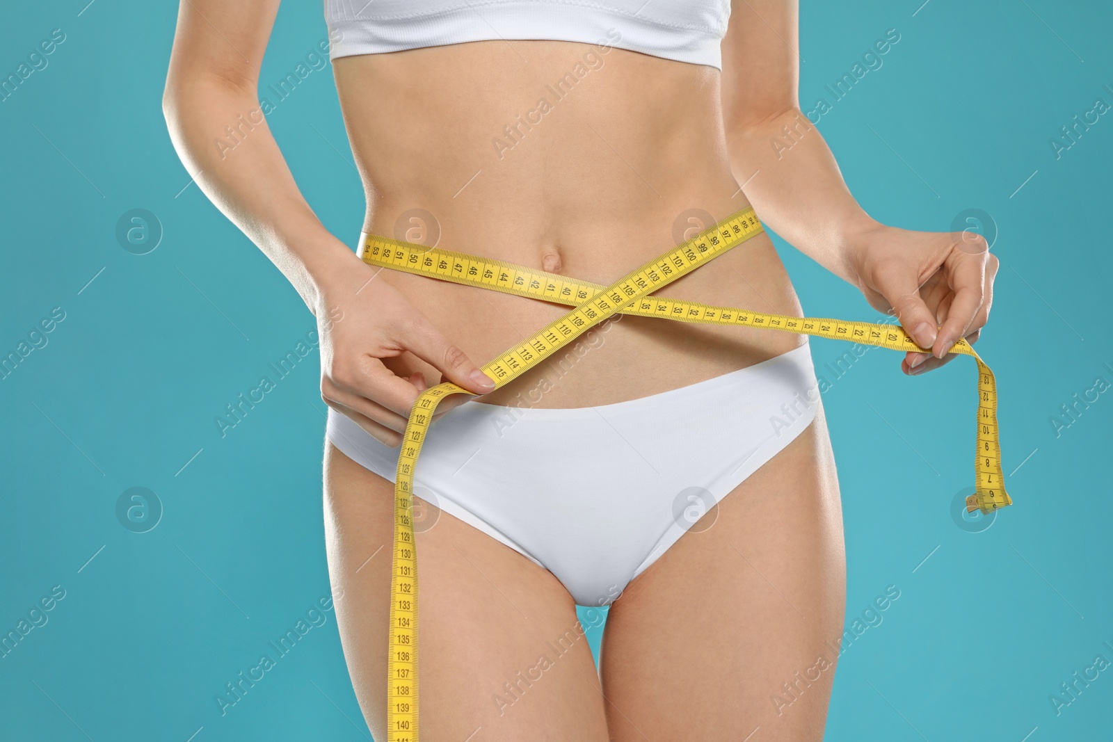 Photo of Slim young woman with smooth gentle skin in underwear measuring body on color background, closeup