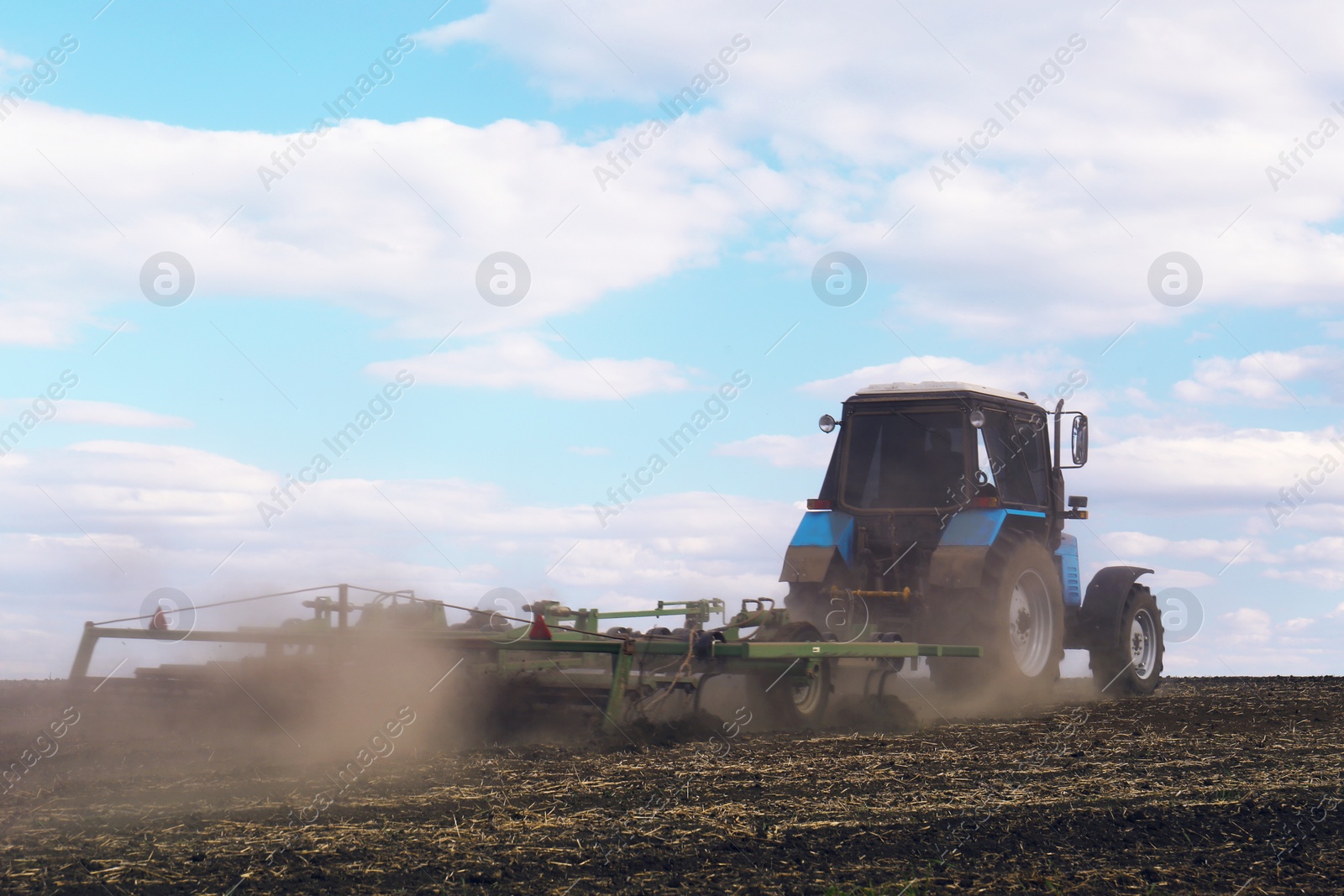 Photo of Tractor with planter cultivating field on sunny day. Agricultural industry