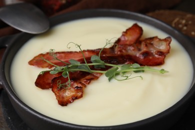 Photo of Delicious potato soup with bacon and microgreens in bowl served on table, closeup