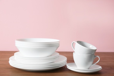 Set of clean dishes on table against color background