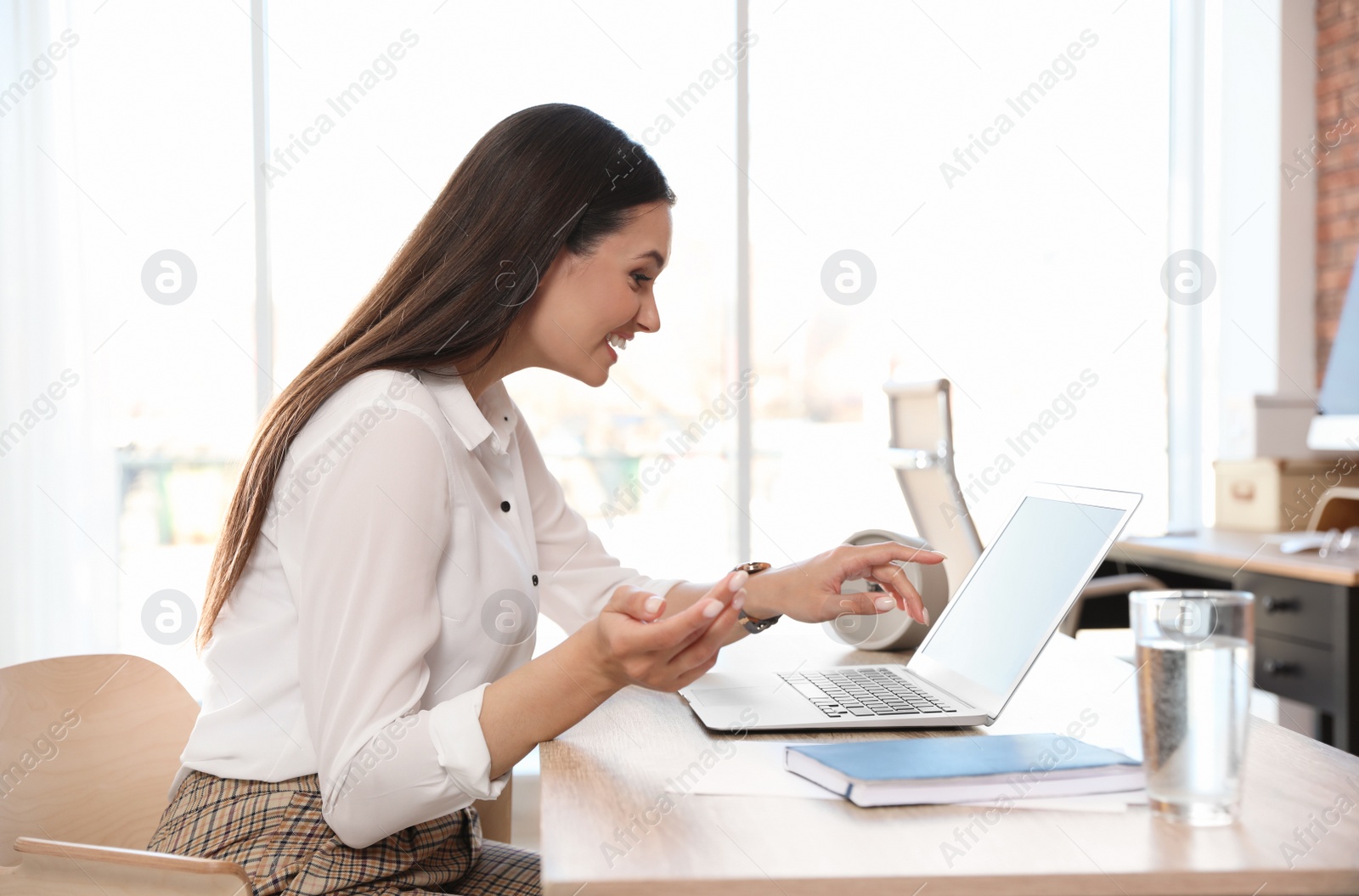 Photo of Young woman using video chat on laptop in home office