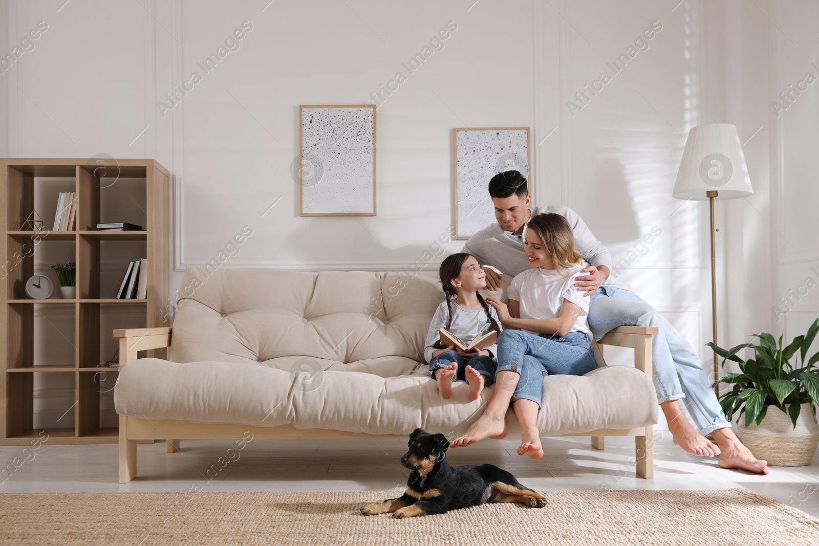 Photo of Happy family on sofa and puppy in living room