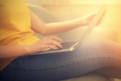 Image of Woman working with laptop on sofa at home, closeup