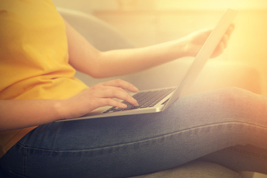 Woman working with laptop on sofa at home, closeup