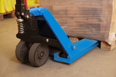 Image of Manual forklift with wrapped pallets in warehouse, closeup. Logistics concept