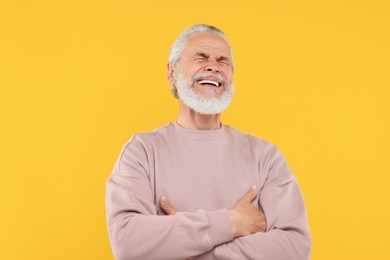 Photo of Portrait of emotional senior man on orange background
