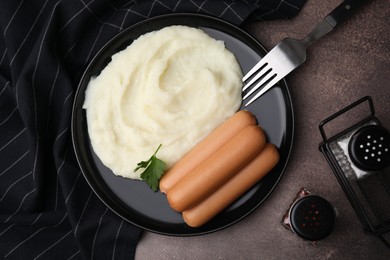Photo of Delicious boiled sausages and mashed potato served on brown table, flat lay